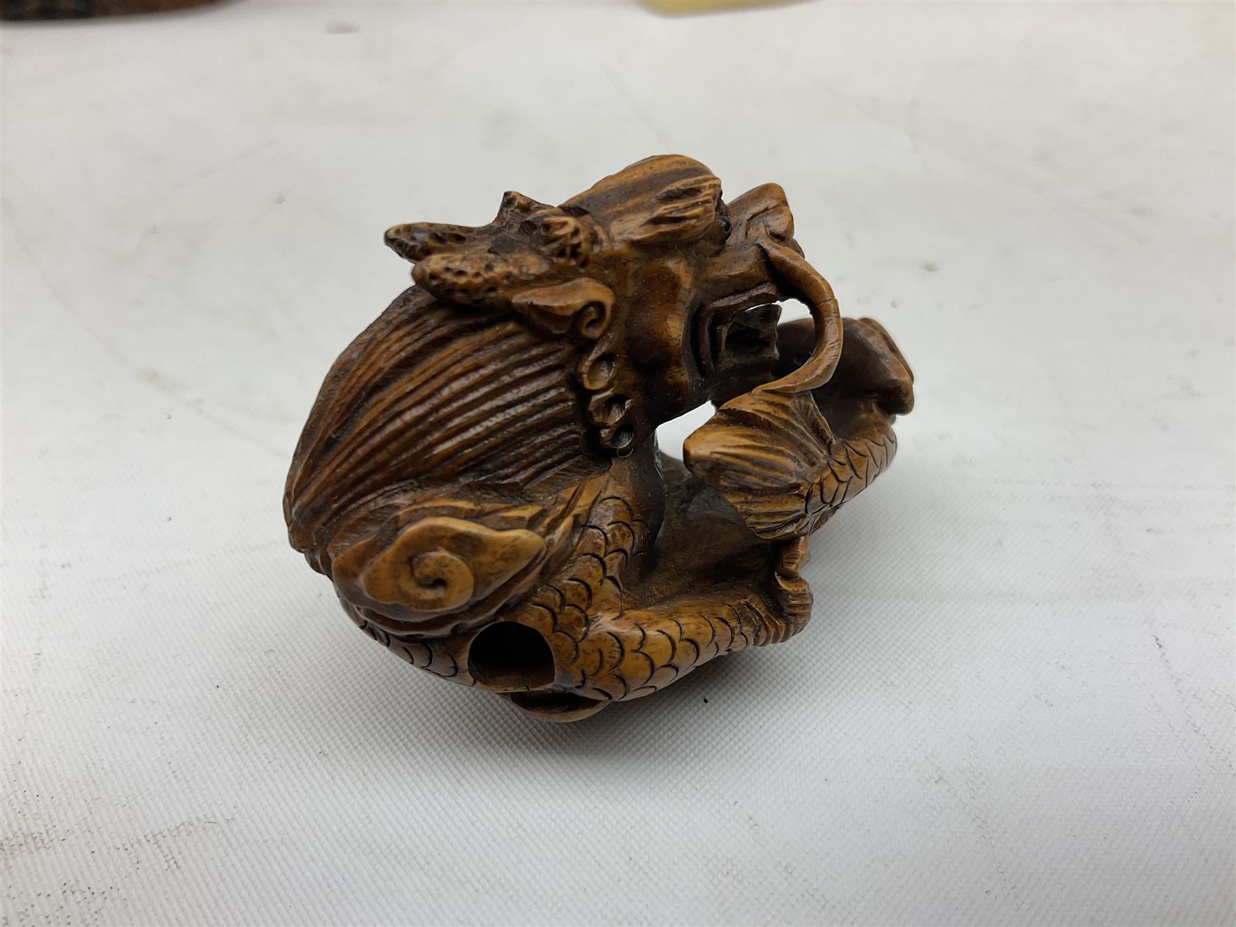 Hardwood bust of an Indoniesian Goddess, carved wearing a pierced headdress, from Klungkung, Bali, H20cm, together with a pair of bone carvings of deity figures, and a carved wood Netsuke in the form of a Chinese dragon