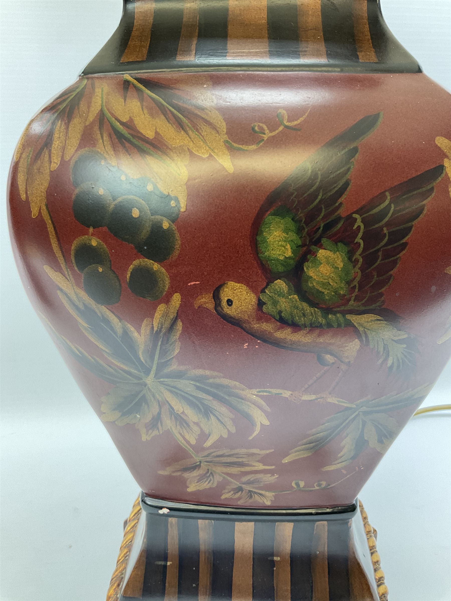 Pair Oriental table lamps decorated with birds in a tree with fruit, on a red ground with a gilded base together with cream lampshades H57cm, without lampshade. 