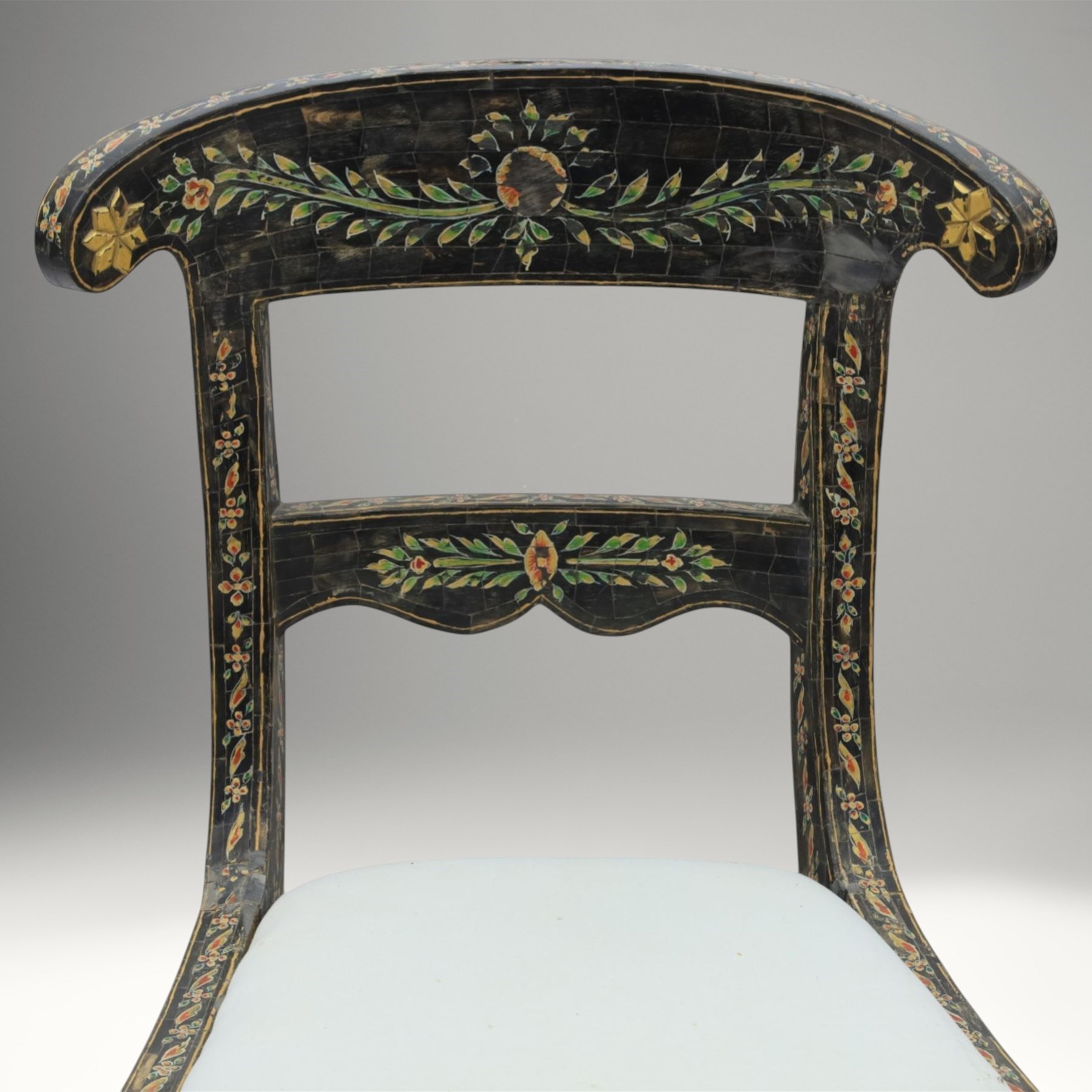 Early 20th century Anglo-Indian painted and inlaid armchairs, each with shaped top rail decorated with polychrome floral motifs above turned spindle galleries, shaped open arms and upholstered seats, on square supports with similar painted decoration