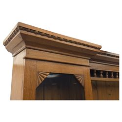 Late 19th century pine dresser, the projecting cornice with dentil and spindle moulded frieze above a three-tier plate shelves, flanked by glazed doors, the base fitted with three frieze drawers over arched apron and carved floral panelled cupboard doors, raised on turned feet