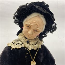 Anna Meszaros Hungary - hand made needlework figurine 'The Great Grandmother' as a pensive old lady seated on a stool wearing a long lace trimmed black and emerald green dress and hat, holding a lace handkerchief H30cm  Auctioneer's Note: Anna Meszaros came to England from her native Hungary in 1959 to marry an English businessman she met while demonstrating her art at the 1958 Brussels Exhibition. Shortly before she left for England she was awarded the title of Folk Artist Master by the Hungarian Government. Anna was a gifted painter of mainly portraits and sculptress before starting to make her figurines which are completely hand made and unique, each with a character and expression of its own. The hands, feet and face are sculptured by layering the material and pulling the features into place with needle and thread. She died in Hull in 1998.