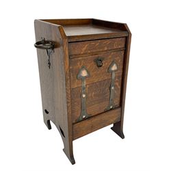 Early 20th century Arts & Crafts oak coal purdonium, sloped form, the hinged fall front with stylised metal strapping, solid ends with pierced decoration terminating to splayed feet, with copper carrying handle, the interior with metal lining and coal shovel