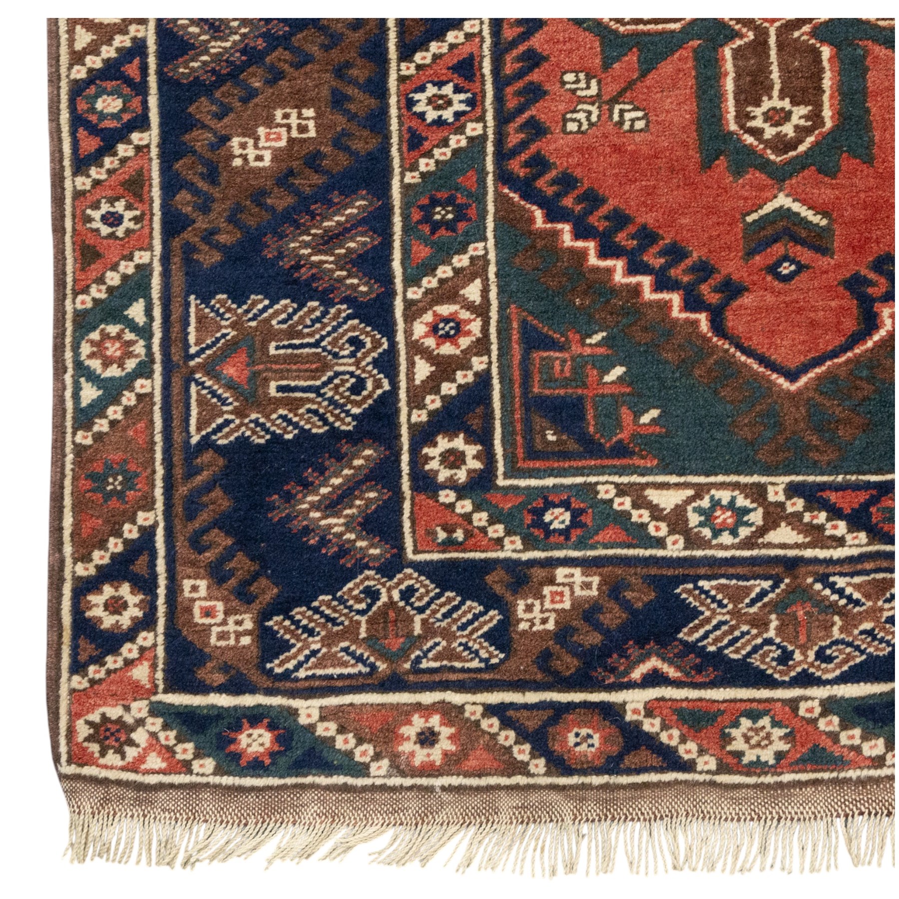 Caucasian Kazak rug, red field with three bold geometric medallions in dark blue, cream and brown, scattered tribal motifs, broad indigo border decorated with stylised hooked forms and multiple narrow patterned borders