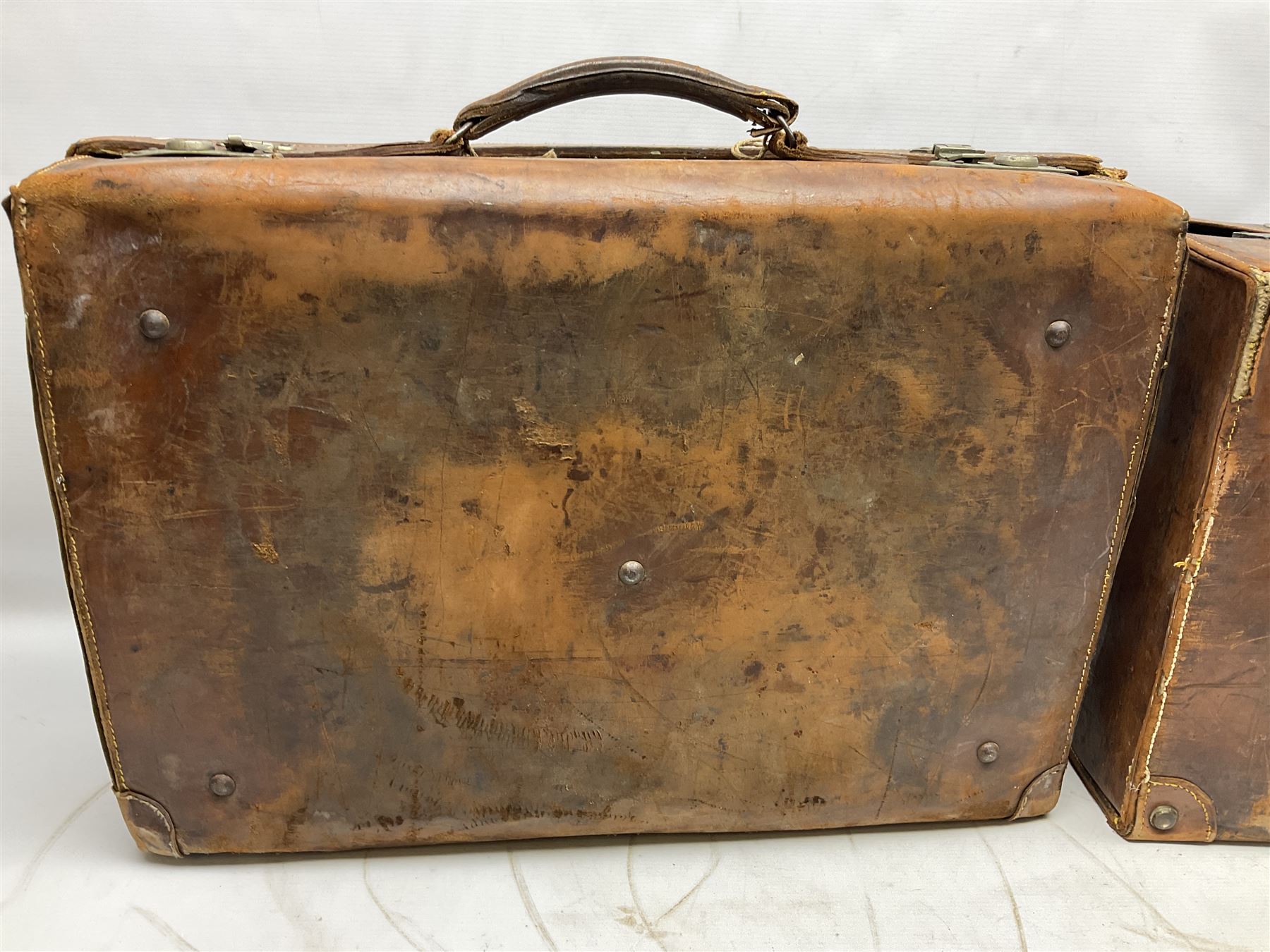 Early 20th century leather suitcase marked to the top 'Major P.M. Newton R.E. Crossways, Bridlington, East Yorkshire' 60 x 40cm; another similar leather suitcase marked W.D. to the lid; three post-WW2 respirators; and three unopened pairs of British Army N.B.C. (Nuclear Biological Chemical) No.1 Mk.III Trousers Protective (8)