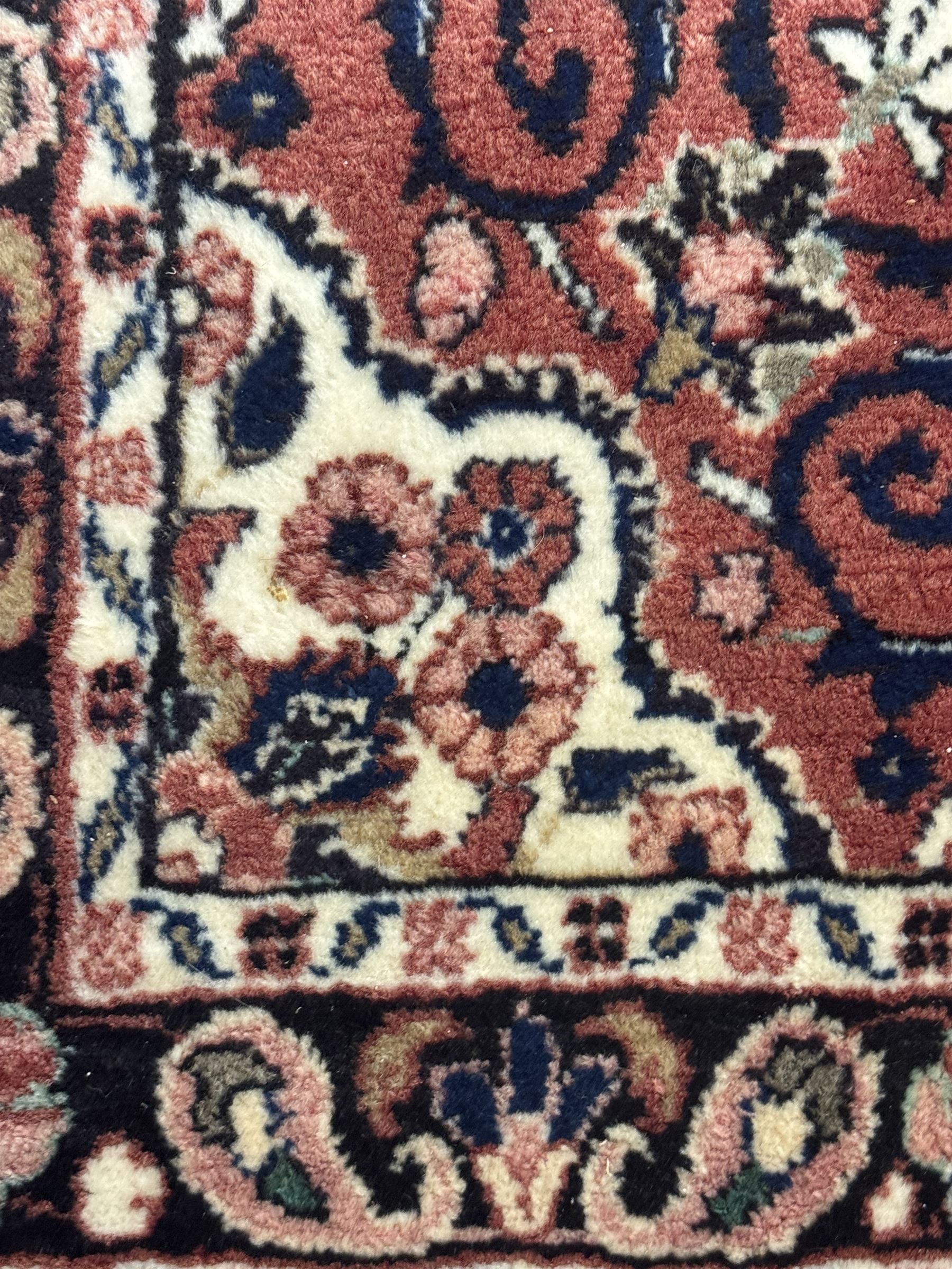 Persian Herati design indigo and red ground carpet, decorated with floral motifs, arched border