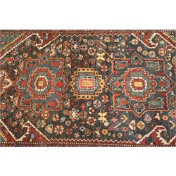 Antique Persian Qashqai dark indigo ground tribal rug, the busy field decorated with a geometric triple pole medallion surrounded by numerous stylised plant motifs with contrasting cyan spandrels, the multiple guard bands woven with stylised palmettes and foliage