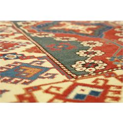 Caucasian Soumak rug, red madder field and teal panels, with bold stepped diamond medallion with hooked motifs and cruciform devices, and floral rosette clusters, surrounded by an ivory border with large hooked diamonds and stylized ram's horn devices, flanked by narrow guard stripes




