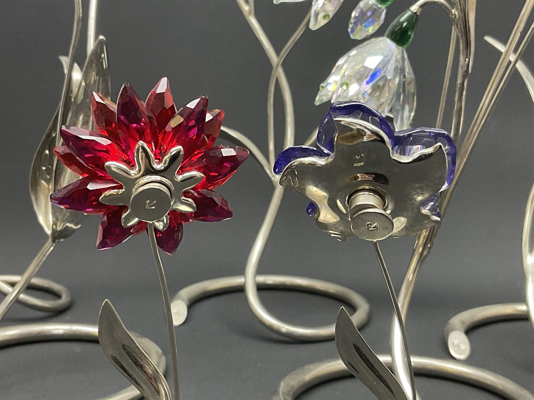 Eleven Swarovski Crystal flowers, to include violet, sunflower, delphinium, forget-me-not and lily-of-the-valley, each on stylised metal stems, tallest H23cm