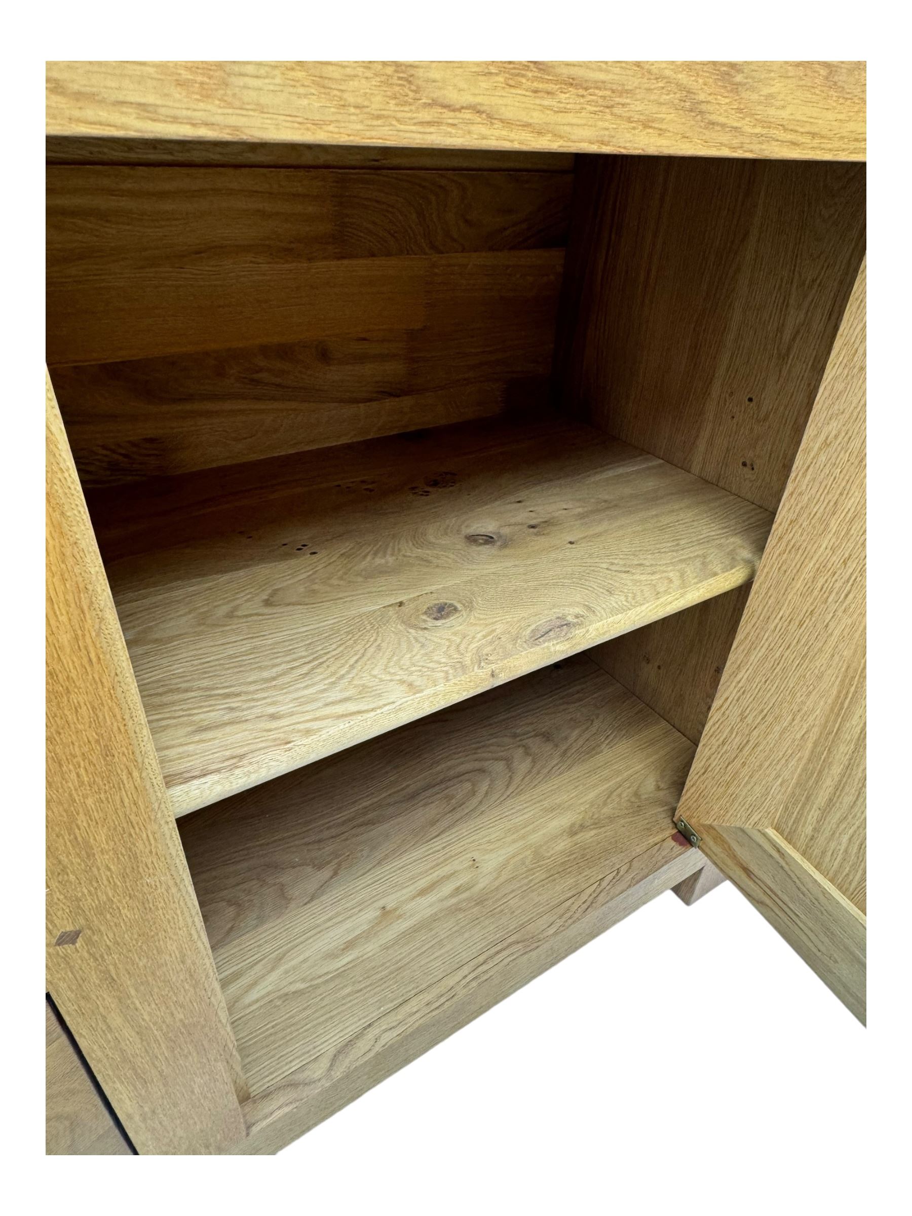 Contemporary light oak sideboard, chamfered rectangular top over two central bevel-edged drawers, flanked by two recessed panelled cupboards enclosing shelving, on square stile supports