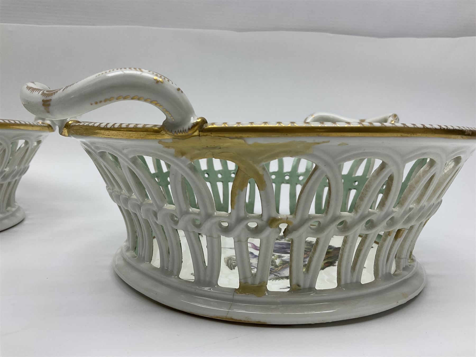 Pair of 19th century German openwork chestnut baskets, with twin handles and scrolling gilt border and star rim, painted to the centre with birds and insects, D22cm 