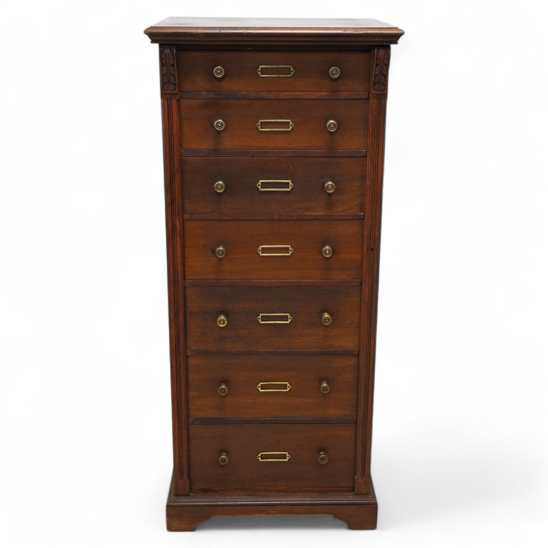 Thomas Edwards & Sons (Newcastle 1877-1882) - Victorian walnut Wellington chest, rectangular moulded top over seven graduating drawers, each fitted with brass handles and label holders, flanked by foliate carved brackets over reed-moulded and chamfered uprights, on shaped skirted base
