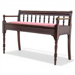 Early 20th century mahogany hall bench, spindle turned back with shaped top rail and open arms terminating in ball finials, upholstered seat within a fluted frieze, raised on turned tapering supports