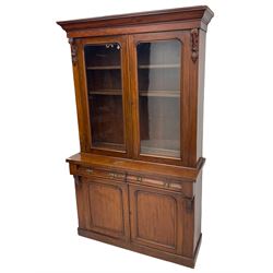 Victorian mahogany bookcase on cupboard, projecting cornice over two glazed doors and carved corbels, fitted with two drawers and double cupboard, plinth base