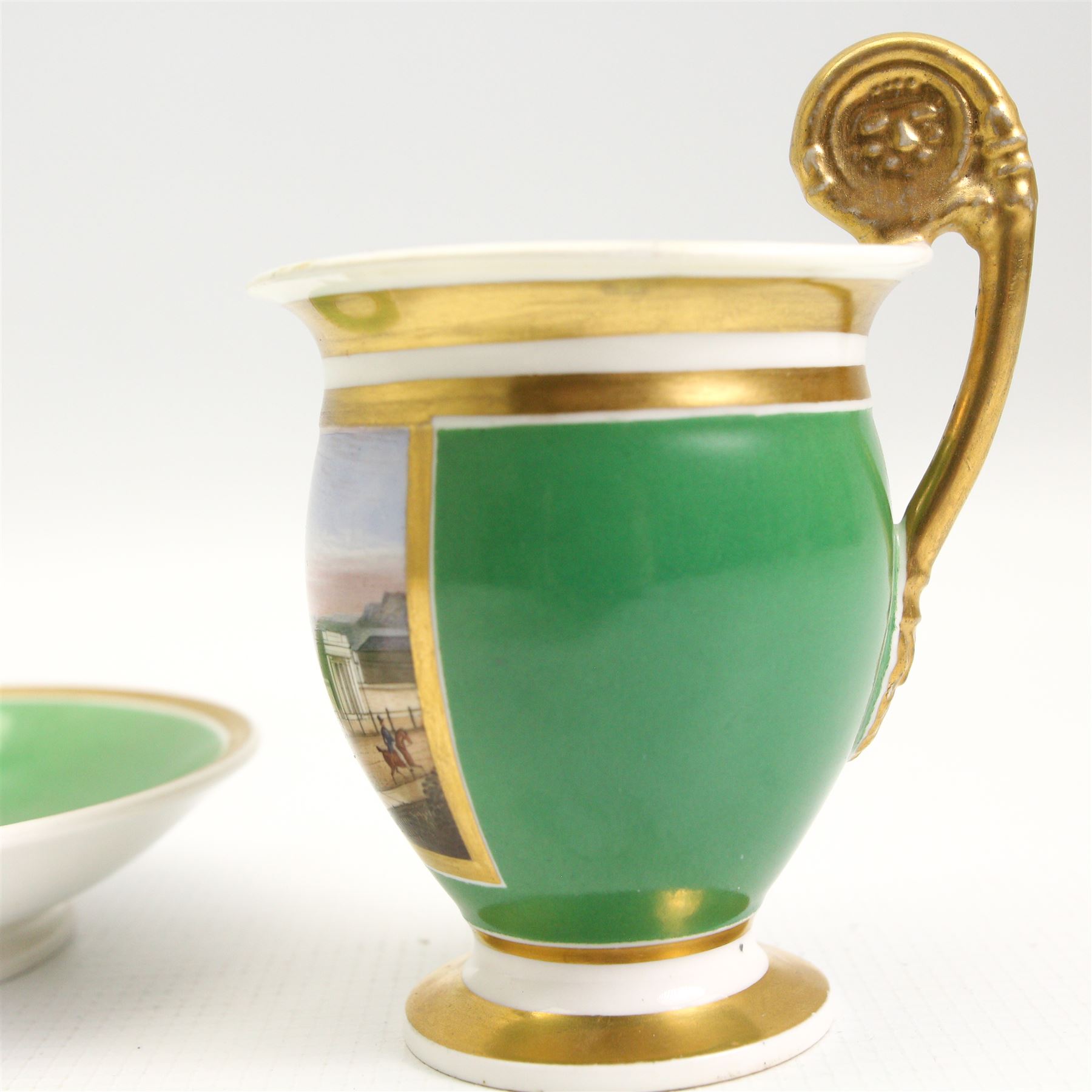 19th century French Empire design porcelain cup and saucer, the cup hand painted with a panel, titled beneath 'Library, St Leonards, Near Hastings', against a green and gilt ground, cup H10.5cm 