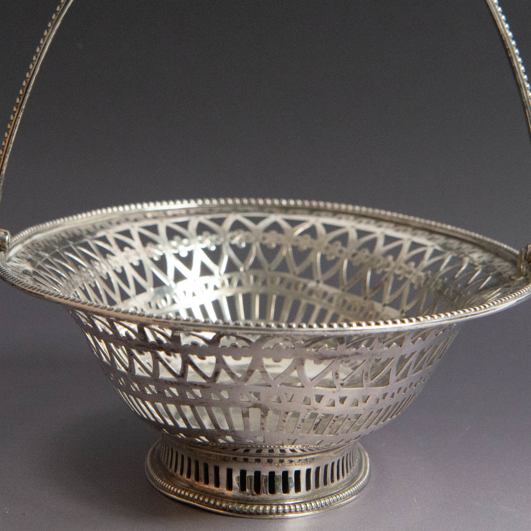 George III silver bon bon basket, of oval form with bead rim and swing handle, the sides with pierced latticework decoration, hallmarked Hester Bateman, London 1785, handle H14cm