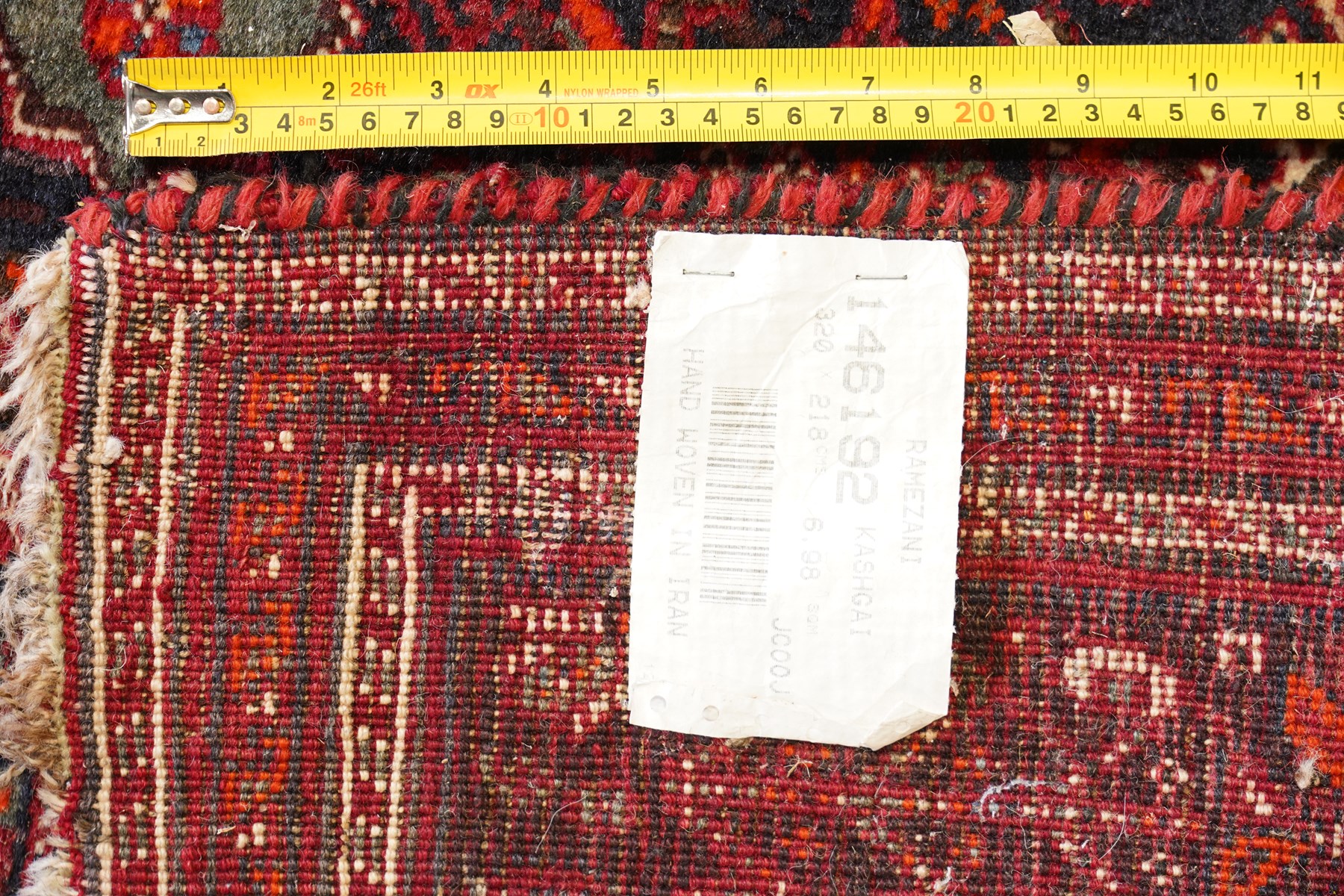 Large Persian Shiraz crimson ground carpet, the busy field decorated with a geometric pole medallion surrounded by stylised plant motifs with contrasting indigo spandrels and geometric-woven guard bands