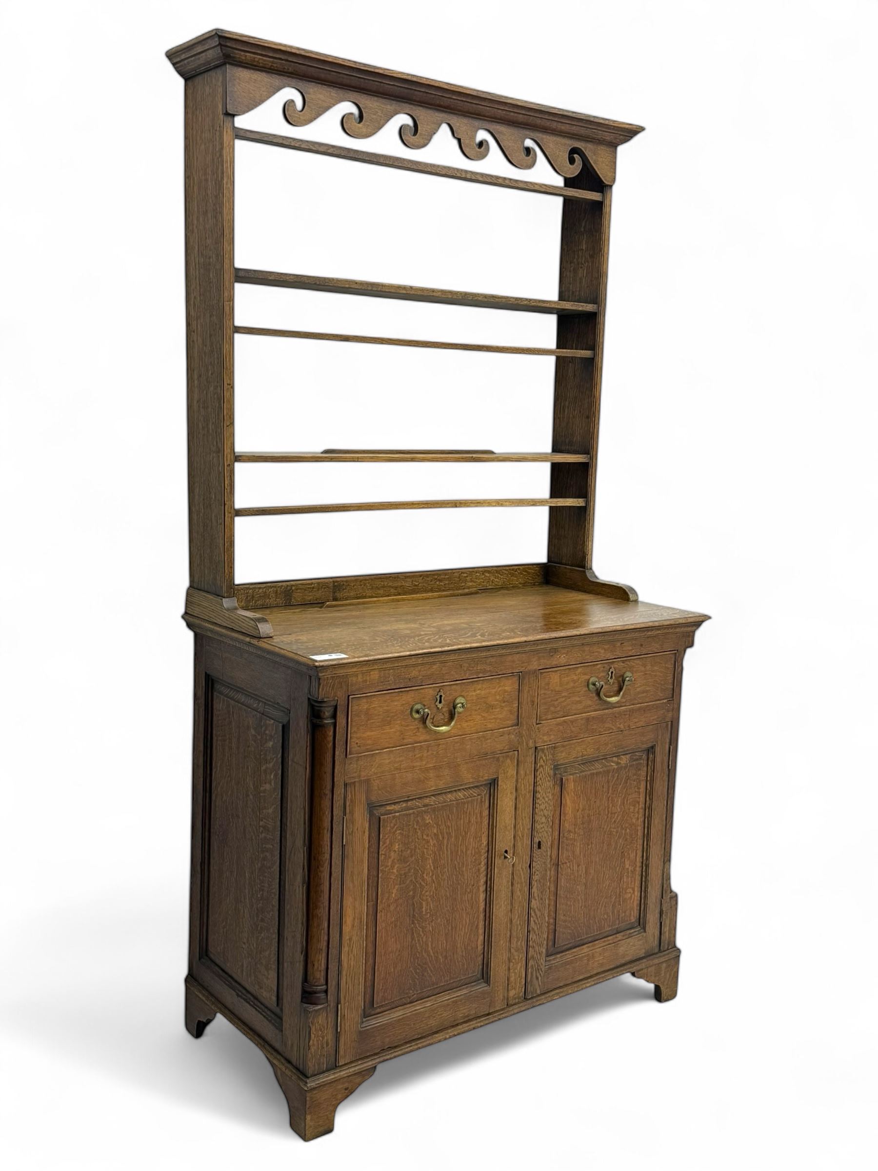 19th century and later oak dresser, moulding cornice a pierced and shaped frieze, over two open plate shelves above a base fitted with two drawers with brass swan neck handles, over panelled twin cupboard with single shelf, cantered corners on bracket feet