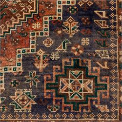 South West Persian Qashqai hand-knotted rug, salmon pink field with central stepped geometric medallion with issuing stylized tree and floral motifs, surrounded by angular devices, with indigo spandrels and multiple geometric borders, fringe ends 