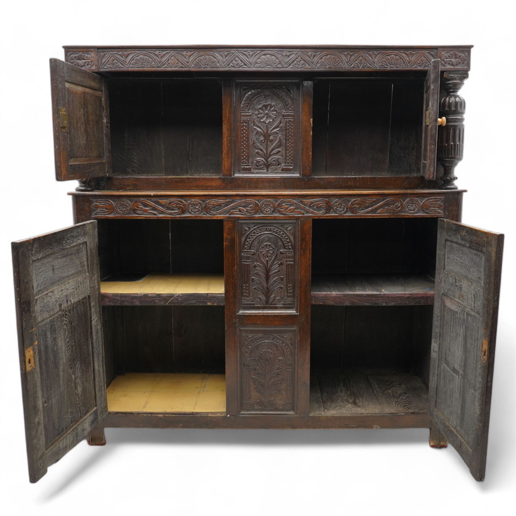 William & Mary design oak court cupboard, lunette carved frieze rail on turned and stop-fluted columns, the upper section fitted with two panelled doors carved with scrolling foliage and shield within a chip-carved border, central panel carved with arcade surrounding flower, foliate S-scroll lower frieze rail over two further cupboards and central panels, each carved with lozenges and curling foliage, moulded and pegged frame, terminating to stile supports 