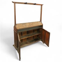Early 20th century oak saddle and tack stand, the sloped top section for saddle storage raised on rectangular panelled base with cupboard doors enclosing shelved interior, with integral upright frame and horizontal rail fitted with three curved tack hook