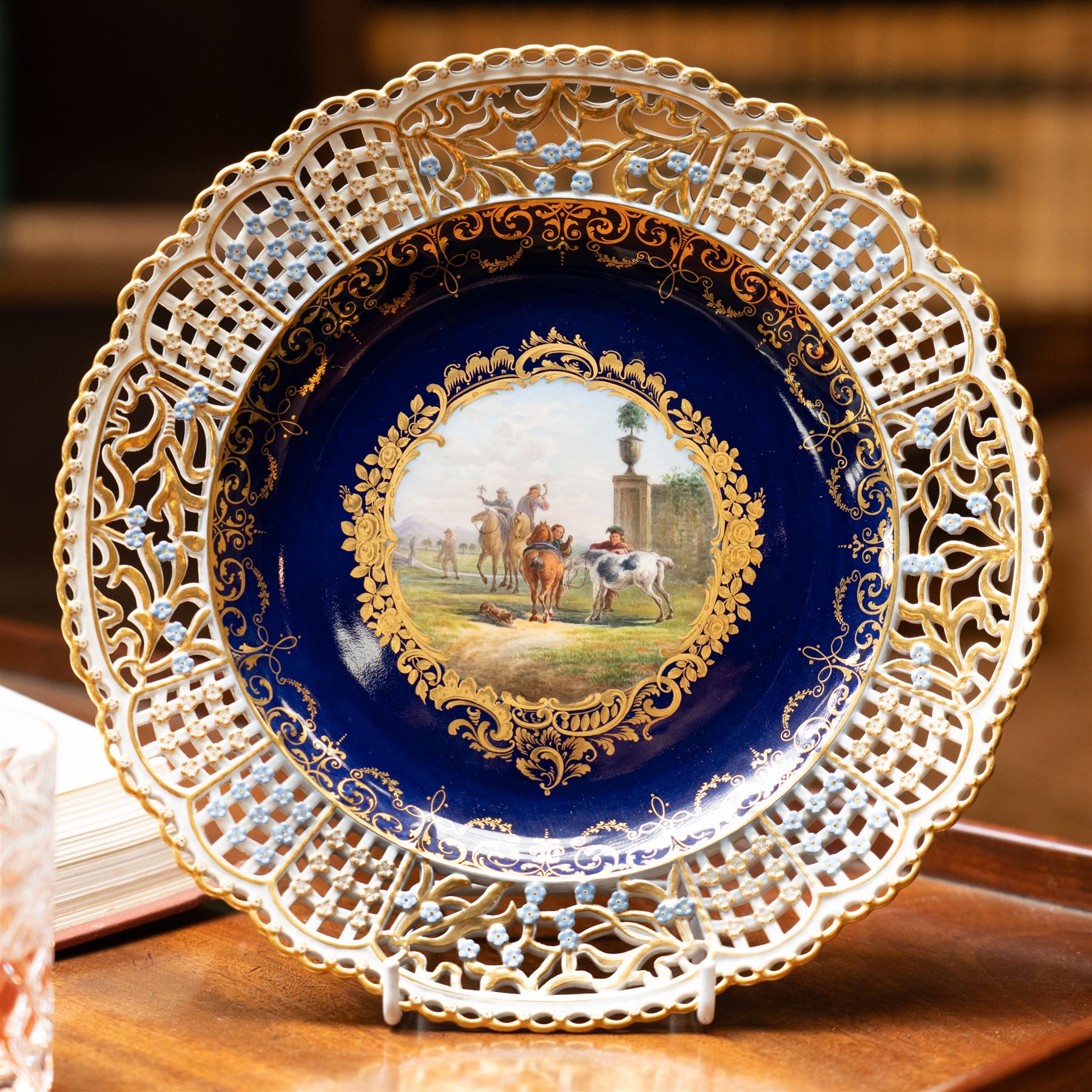 19th century Meissen cabinet plate, the reticulated border modelled with trellis panels and forget-me-nots,  the cobalt blue well with gilt bordered central reserve painted with a scene of a hunting party after Philips Wouwerman (Dutch 1619-1668), underglaze blue crossed swords and indistinct impressed numbers verso, D26cm
