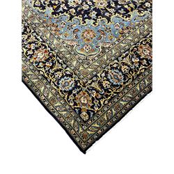 Persian Kashan indigo ground carpet, floral pattern light blue ground central medallion and spandrels, the fielding decorated with interlacing leafy branches and palmettes, the repeating floral pattern border enclosed within guard stripes