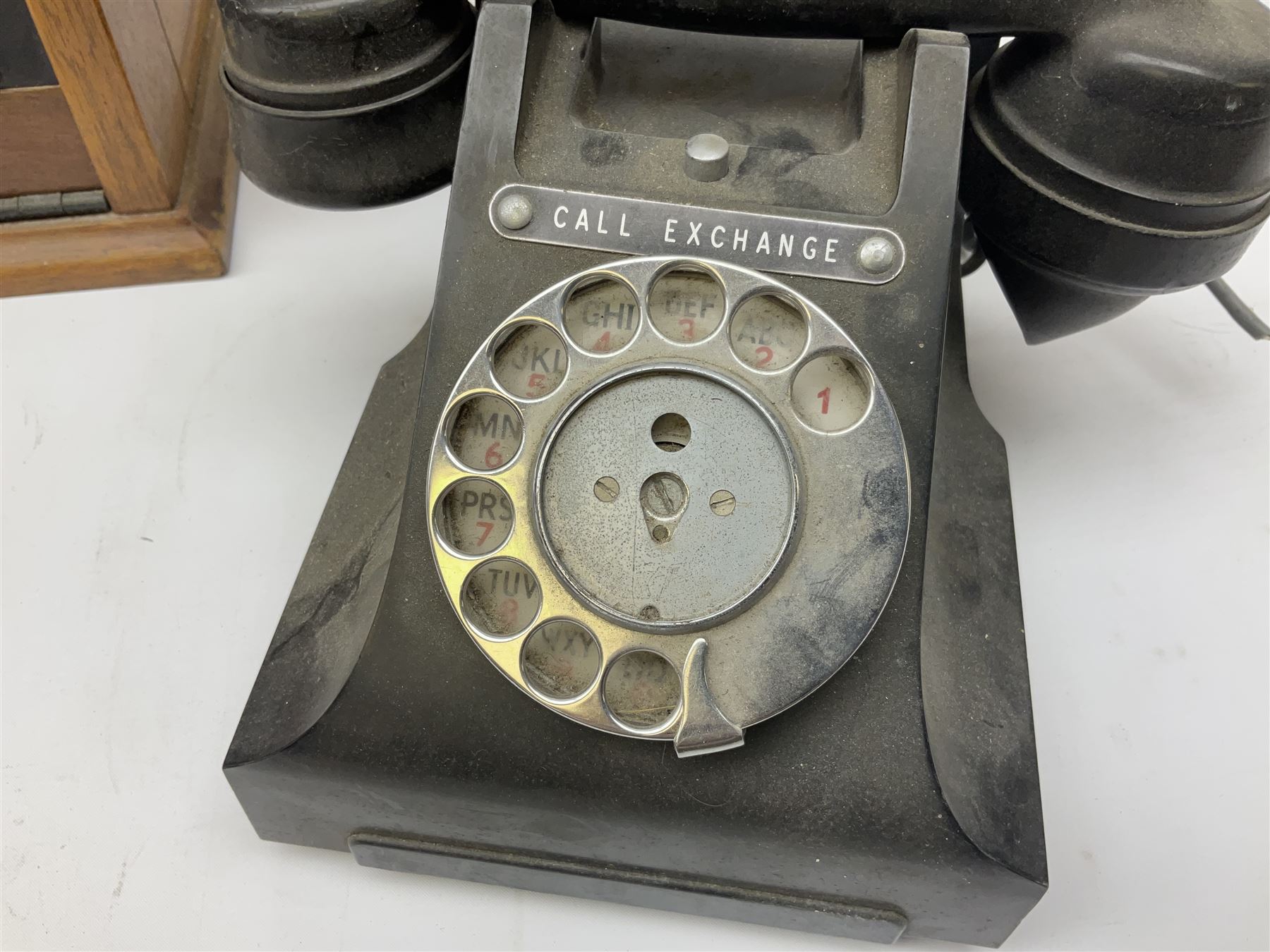 Early-mid 20th century internal telephone system, comprising exchange box with attached TMC rotary telephone and dictograph with Bakelite handset and support upon stained wood case, and 1960s black Bakelite telephone model 312L with G.P.O sticker beneath, largest H30.5cm W36.5cm D30cm