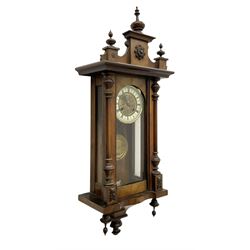 German - late 19th century spring driven wall clock in a walnut and ebonised case, with a fully glazed door and decorative pediment with turned finials, ivorine chapter with Roman numerals and an embossed gilt dial centre, with a repousse pendulum bob and beat plate, twin train movement striking the hours on a coiled gong.