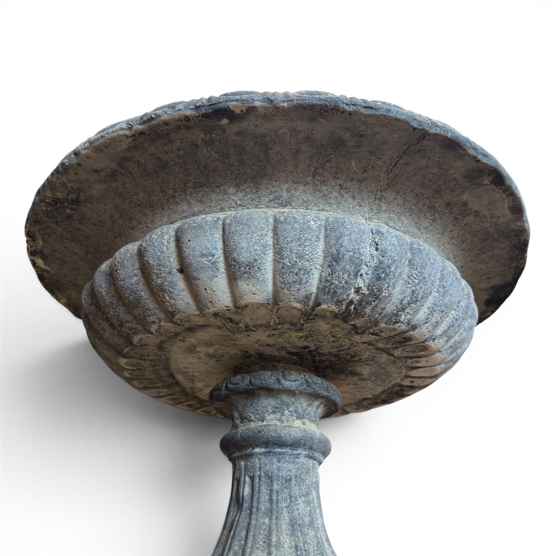 Pair of cast stone garden urns of kylix form on pedestals, the broad egg-and-dart moulded rim over a shallow gadrooned underbelly, with waisted tapering base, raised on matching plinth bases with faux panelled facia