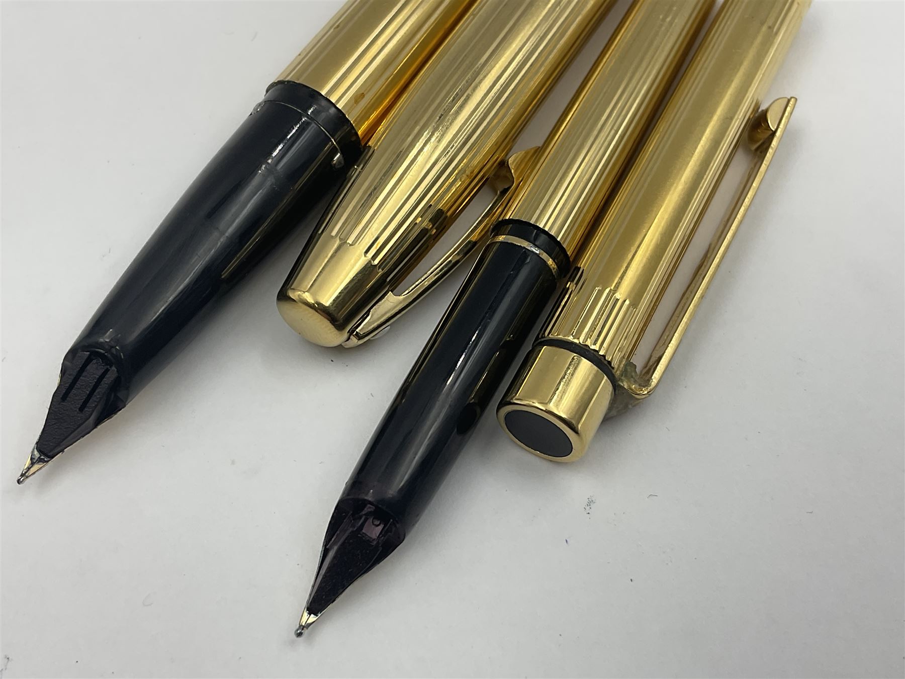 Sheaffer Triumph Imperial fountain pen, the gold plated barrel with fluted stripe design and gold nib stamped 14K 585, together with a Sheaffer Targa slimline fountain pen with gold plated barrel similarly decorated with gold nib stamped 14K 585, ballpoint pen and propelling pencil, each with a fluted gold plated barrel, largest L13.5cm (4)