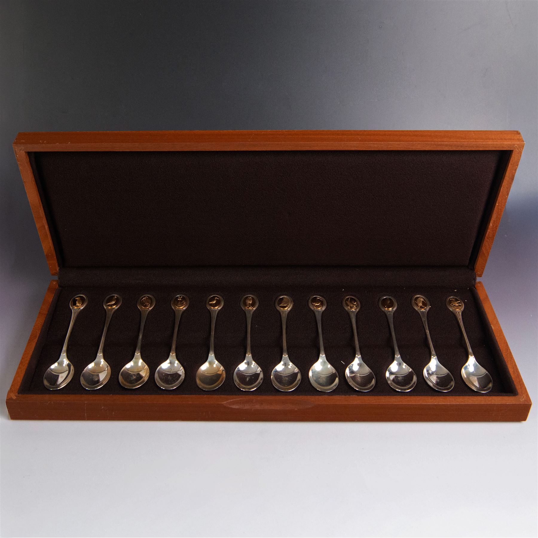 Royal Society for The Protection of Birds silver spoon collection, twelve spoons each inset with a silver-gilt bird cameo, hallmarked John Pinches Ltd, London 1975, in wooden presentation case with certificate of authenticity