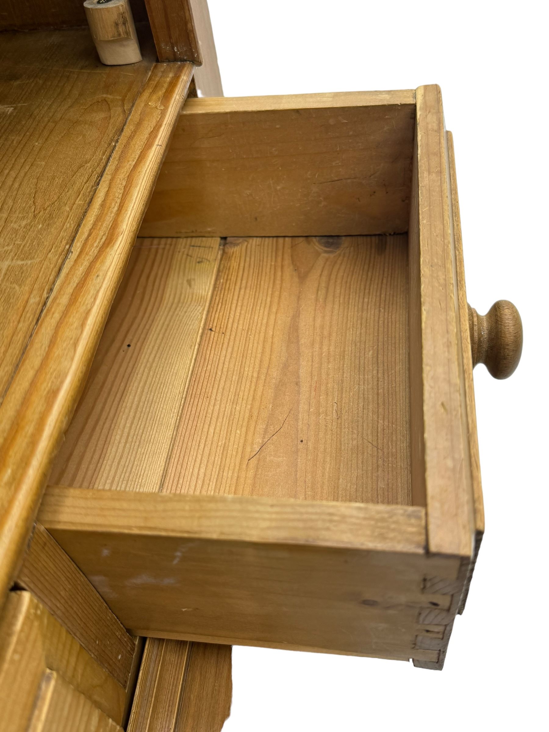 Early 20th century pine kitchen dresser, featuring a hutch with arched top over three open shelves, the base with five drawers over three cupboard doors, turned column supports flanking the doors, scalloped apron base with bracket feet