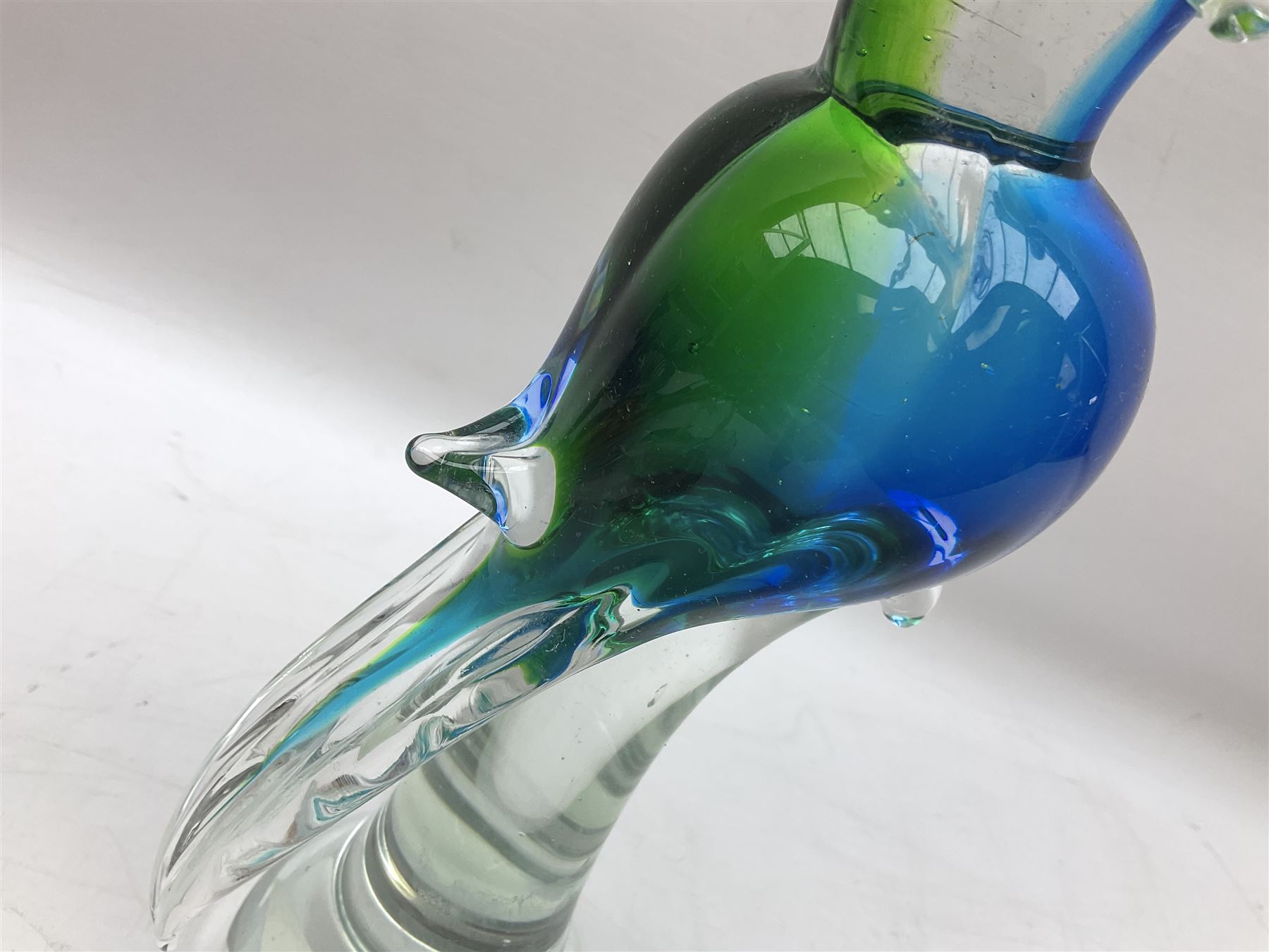 Three Murano style glass cockatoo parrots, the first with mottled yellow, red and orange body, clear outstretched wings, dark blue beak and red crest, raised upon clear stylised base, the second smaller parrot with merging blue and green body, and further with pink striped body, tallest H40cm