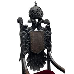 Grand mid-to-late 19th century heavily carved beech framed throne chair, the crown pediment carved with flower heads and cross finial, scroll and acanthus carved upright supports with twin perching griffin back enclosing etched leather work heraldic shield with castle and lion motifs over splayed feathers, flower head carved down sweeping arms with grotesque carved terminals, the seat rails carved with further flower heads on moulded supports with oversized ball and claw carved feet

Provenance: A very similar chair was used in the filming of Stanley Kubrick's 'Eyes Wide Shut' (1999)
