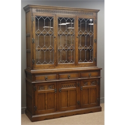  Old Charm oak bookcase display cabinet, projecting cornice, three lead glazed doors enclosing three shelves above cupboard base with three drawers and three cupboards, plinth base, W135cm, H189cm, D46cm  