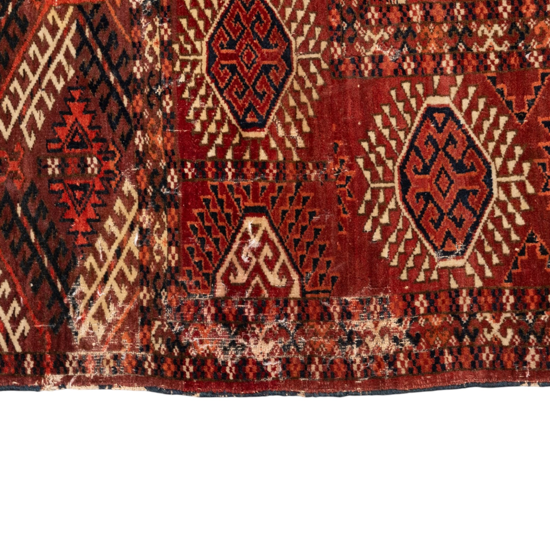 Persian Bokhara crimson ground rug, the field decorated with five rows of repeating Gul motifs with interspersed geometric design, enclosed by a guard band of further geometric-style Gul designs comprised of hook motifs