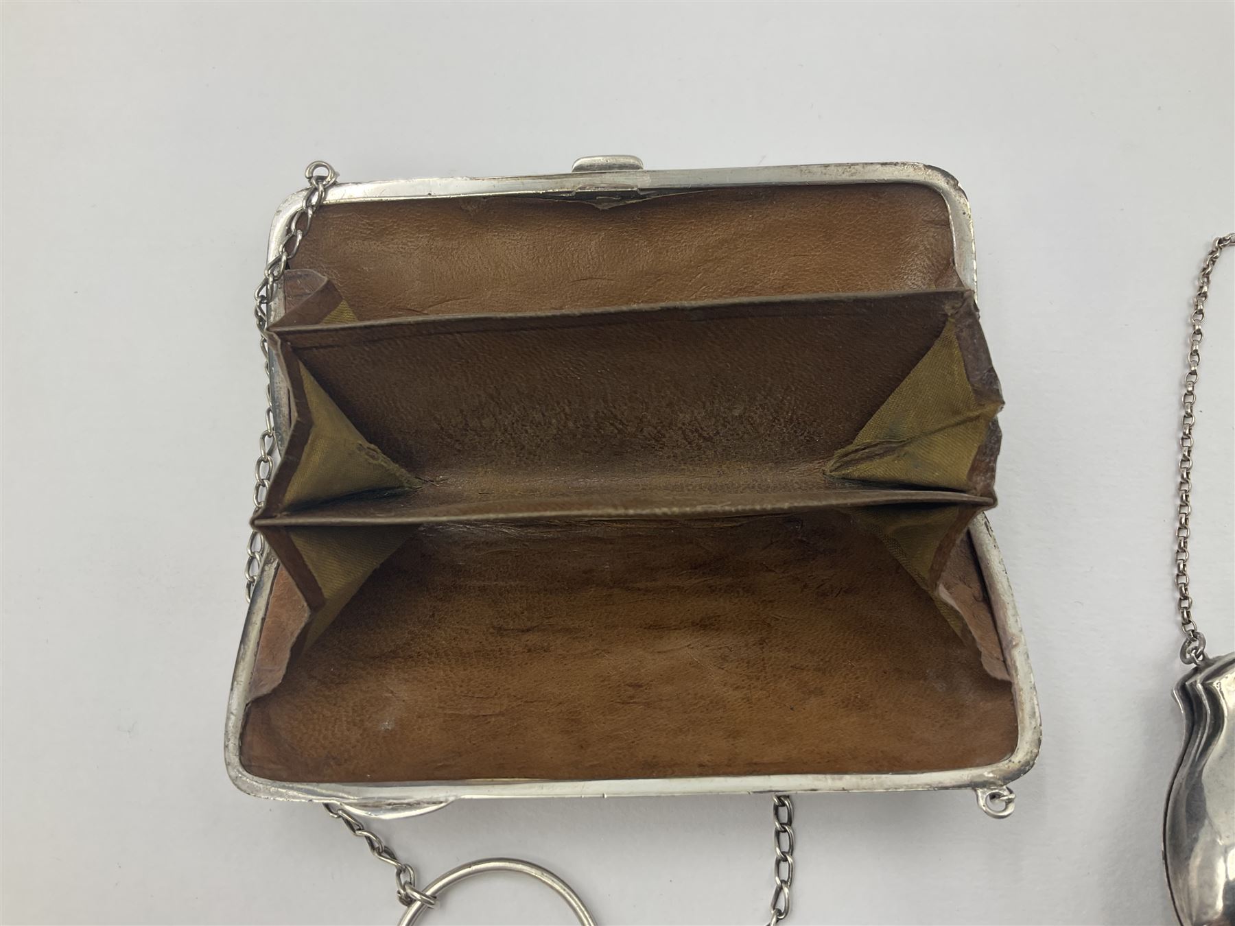 Early 20th century silver mounted coin purse, with leather interior and finger chain, hallmarked Samuel M Levi, Birmingham 1917, together with a similar Edwardian example, with engraved initials and engine turned decoration, hallmarked Birmingham 1907, maker's mark worn and indistinct, largest W11.3cm