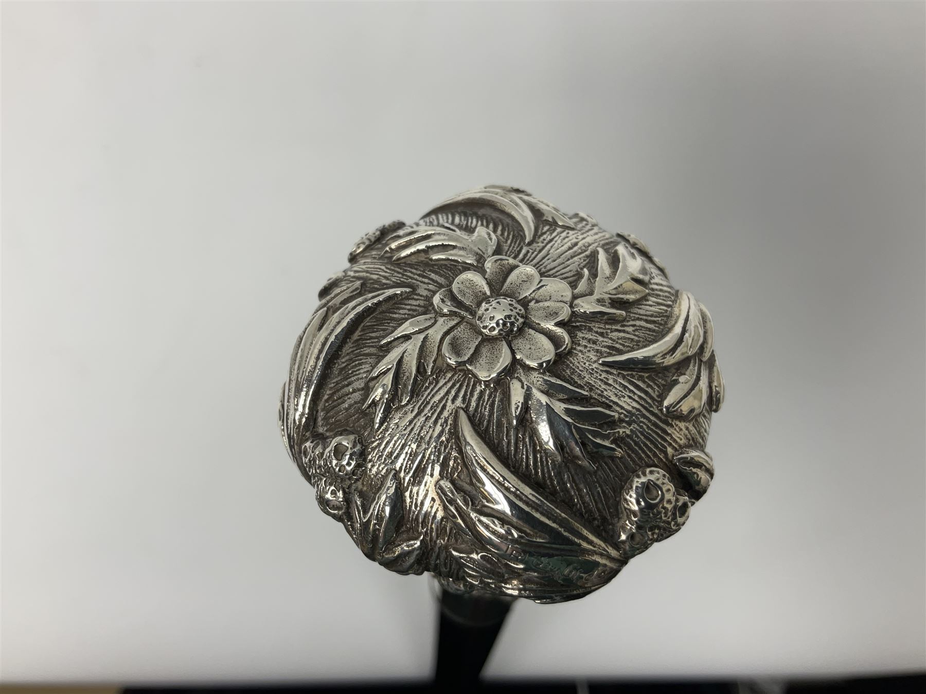 Silver topped walking cane, with embossed decoration in the Victorian taste of flowers, berries and acanthus leaves, stamped 925, upon an ebonised shaft, L94cm