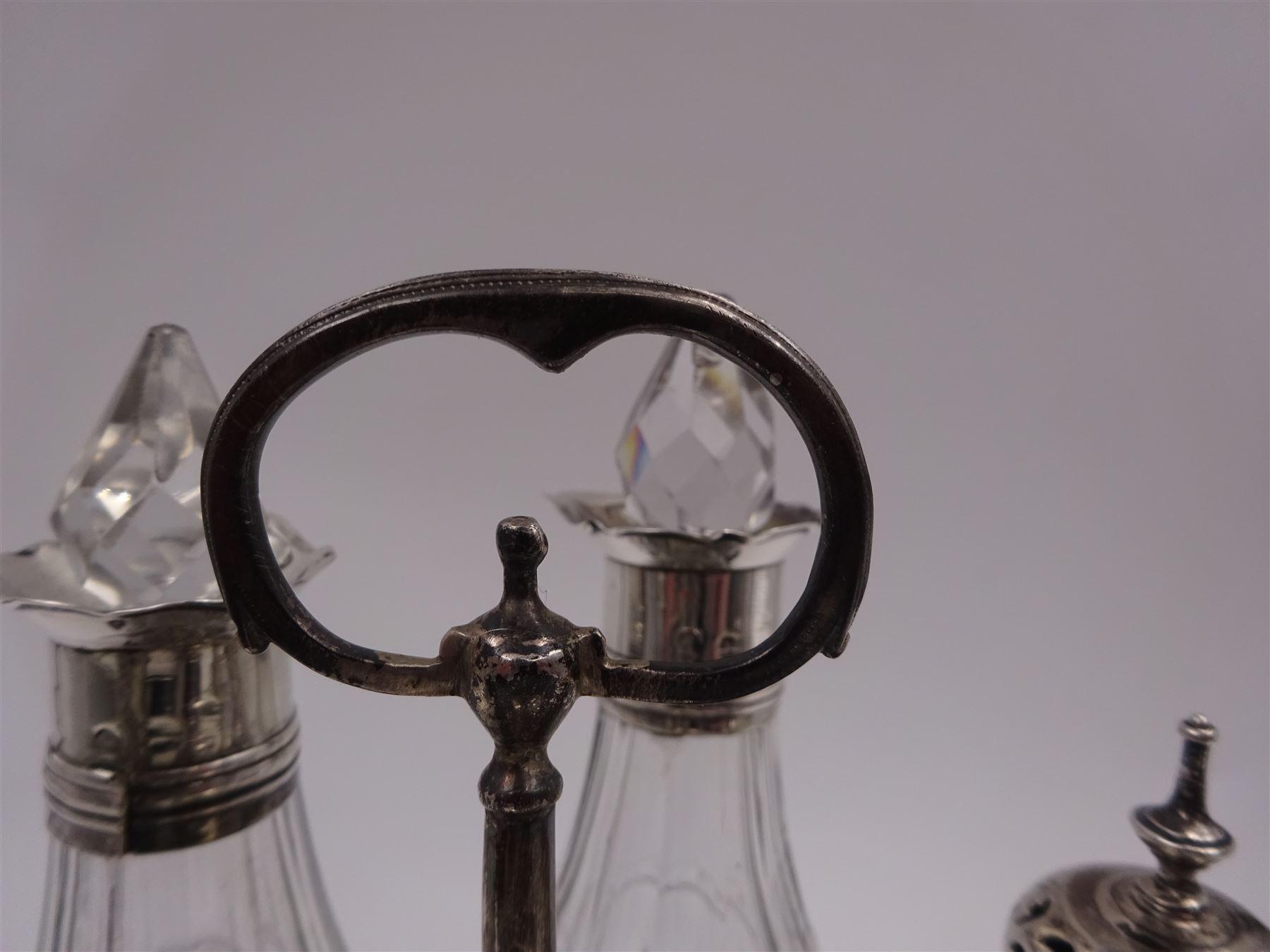 Late 18th century silver cruet stand, of oval form, with pierced sides upon four bun feet, hallmarked to handle Hester Bateman, all other hallmarks indistinct, together with five matched silver mounted cut glass cruet bottles, including some later Victorian examples, hallmarks predominantly indistinct, stand H20cm