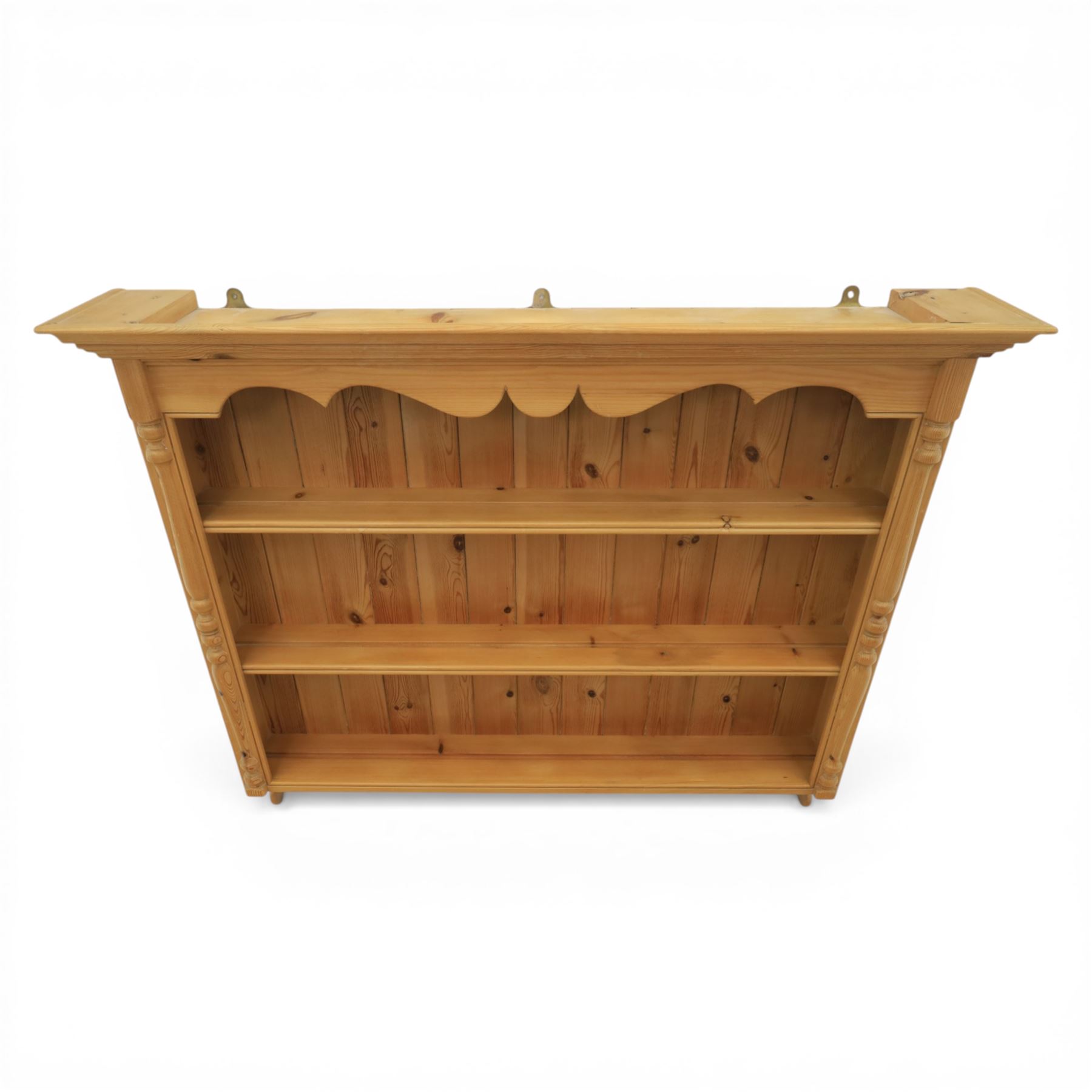 20th century country style waxed pine hanging wall shelf, with projecting cornice, over three fixed delf racks, flanked by applied turned columns, with brass wall hangers