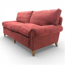 Late 20th century three seat sofa upholstered in red fabric, with gently rounded scroll arms, loose seat and back cushions, raised on tapered wooden legs
