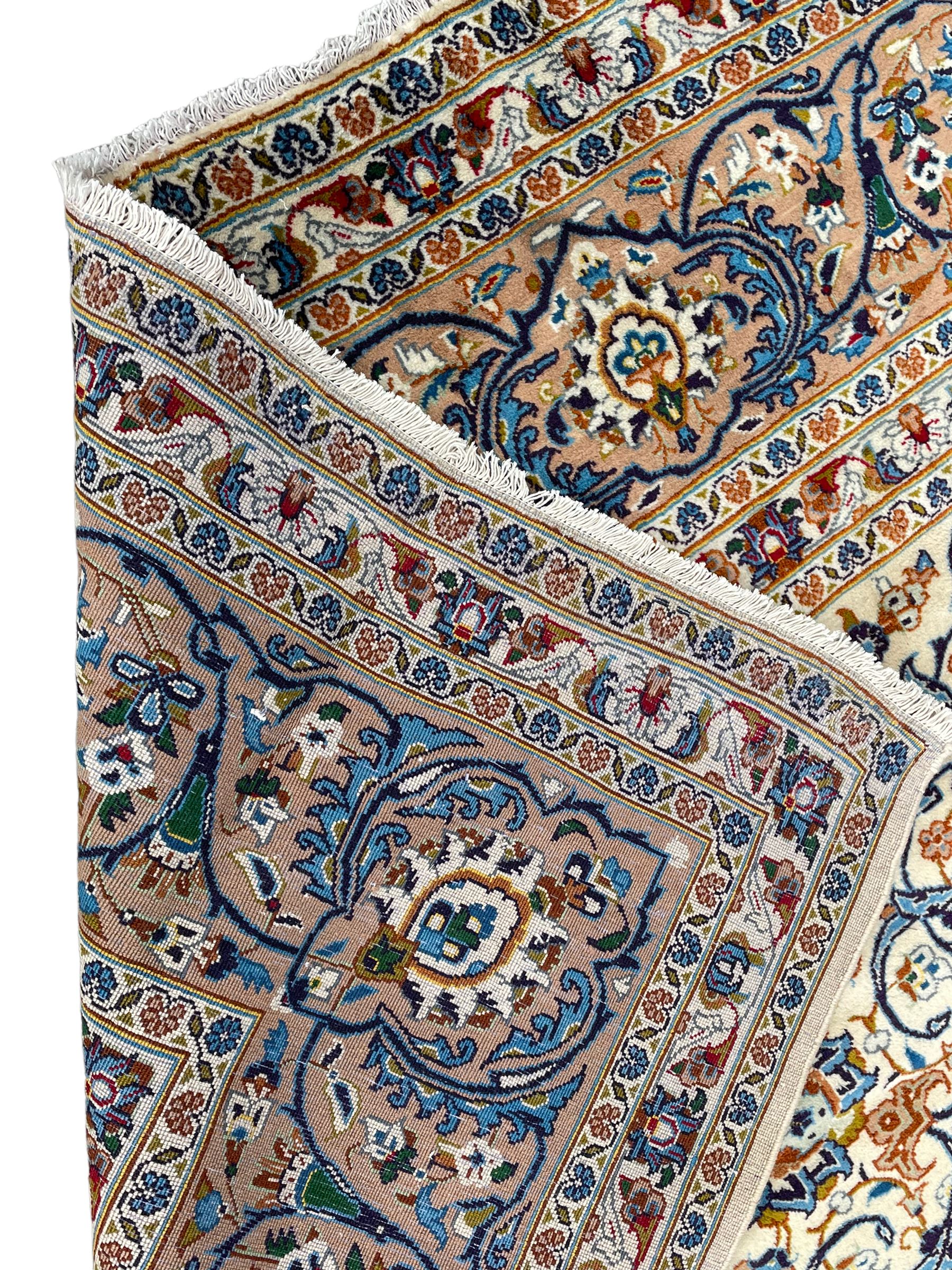 Persian Kashan ivory ground carpet, the interlaced foliate medallion surrounded by trailing plant motifs interlaced with scrolls, the guarded border with repeating stylised flower heads