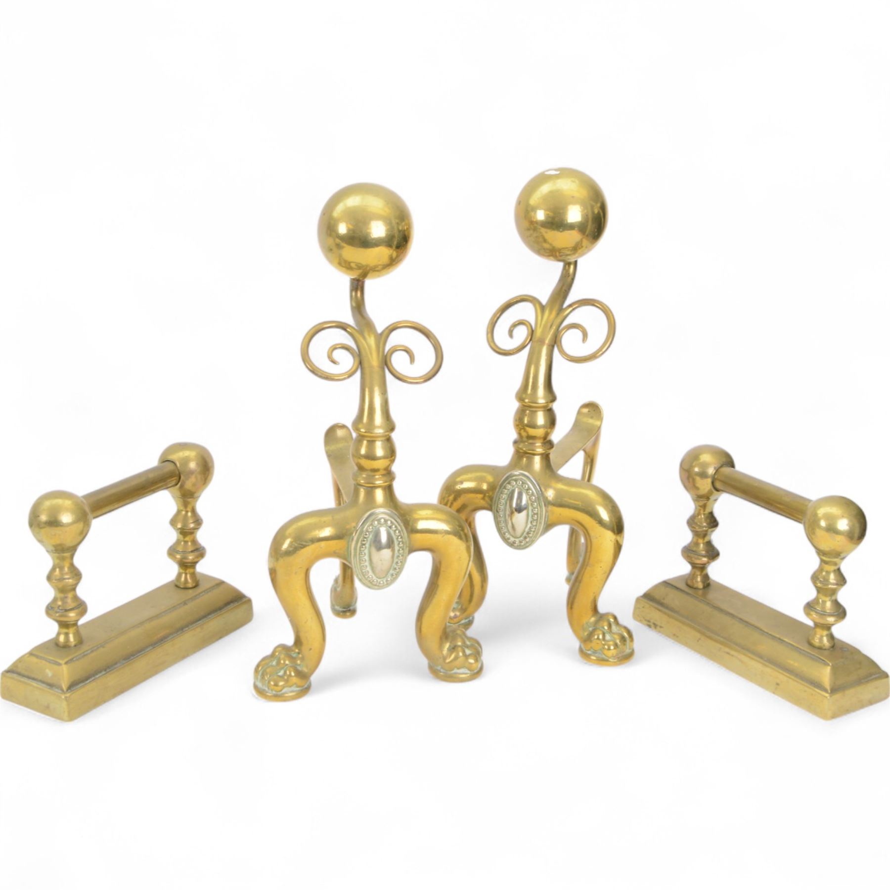 Pair of  Victorian brass fire dogs, decorative brass ball roundels to tops, with a silvered cartouche to the front, raised upon paw feet, together with two other fire dogs, largest H36cm 