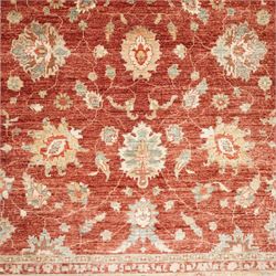 Persian Chubi Oushak style revival hand-knotted carpet, madder red field decorated with large-scale stylized palmettes and floral sprays framed by a broad pale golden border with simplified foliate motifs and multiple guard stripes
