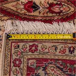 West Central Persian Sarouk hand-knotted carpet, ivory field with central ornate medallion and scrolling vines and palmettes, surrounded by large stylized boteh motifs and flowering foliage, enclosed by a madder-red border of palmettes and floral vine ornament between multiple guard stripes, cotton fringe ends 