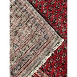 Persian Arak crimson ground rug, the field decorated with repeating Boteh motifs within geometric guard stripes