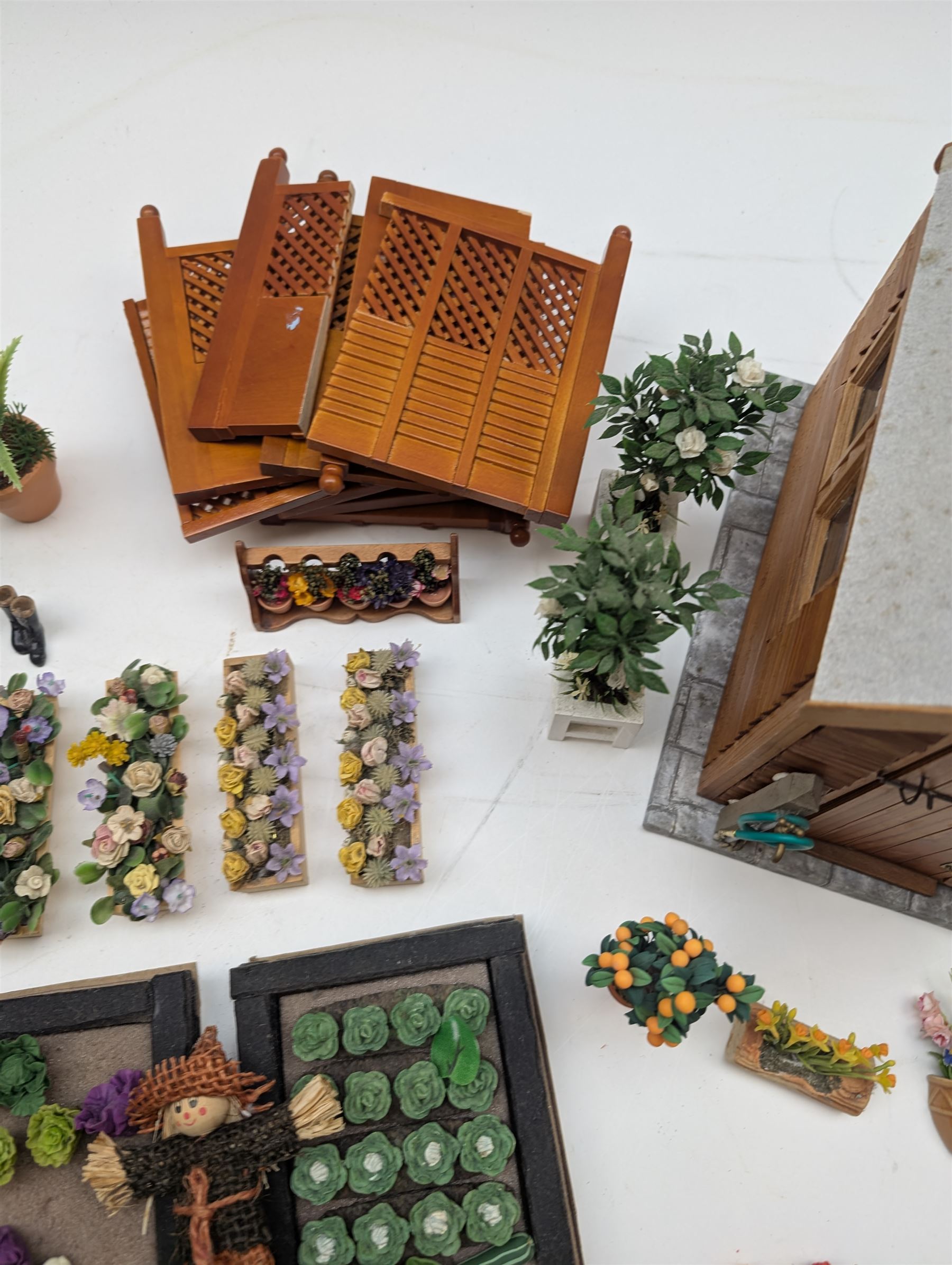 1:12 scale dolls house allotment and garden accessories, including wooden shed on a stone effect base, two vegetable patches, terracotta plant pots with flowers and foliage, stone effect plant pots, other planters, loose sunflowers, scarecrow, rabbit hutch, garden tools, fencing panels, etc 