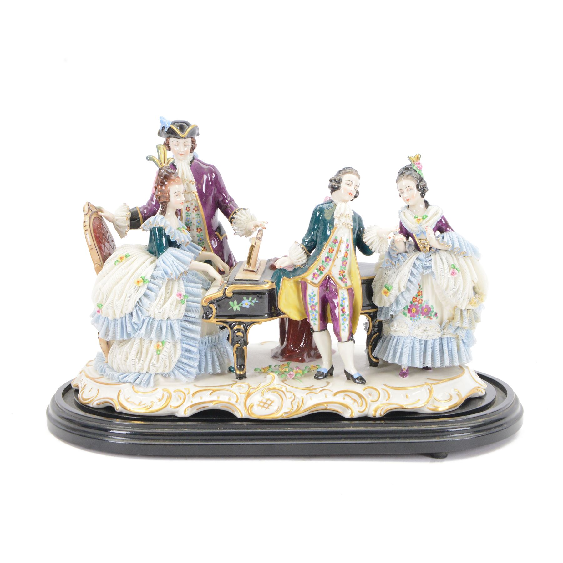 German lace figure group, modelled as a piano recital, the female figures with lace skirts and trimmed gowns, the male figures with lace cuffs and cravats, upon a gilt scrolling base, H22.5cm W33cm 