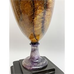 Early 19th century and later Blue John urn, Winnats one vein, of ovoid form with integrated cover and ball finial, upon a spreading circular base, and square stepped black lacquered base, H34.5cm