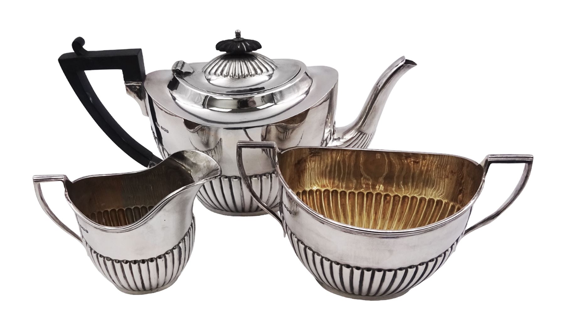 Early 20th century silver three piece tea service, comprising teapot, twin handled sucrier, and milk jug, each of oval part fluted form, the teapot with ebonised handle and finial, hallmarked Sheffield 1918, maker's mark WHM